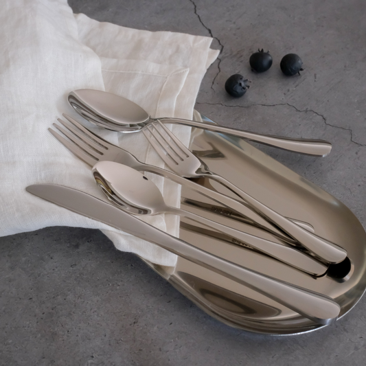 Set of Spoons, forks and knife placed on black marble with tissue and blue-berries