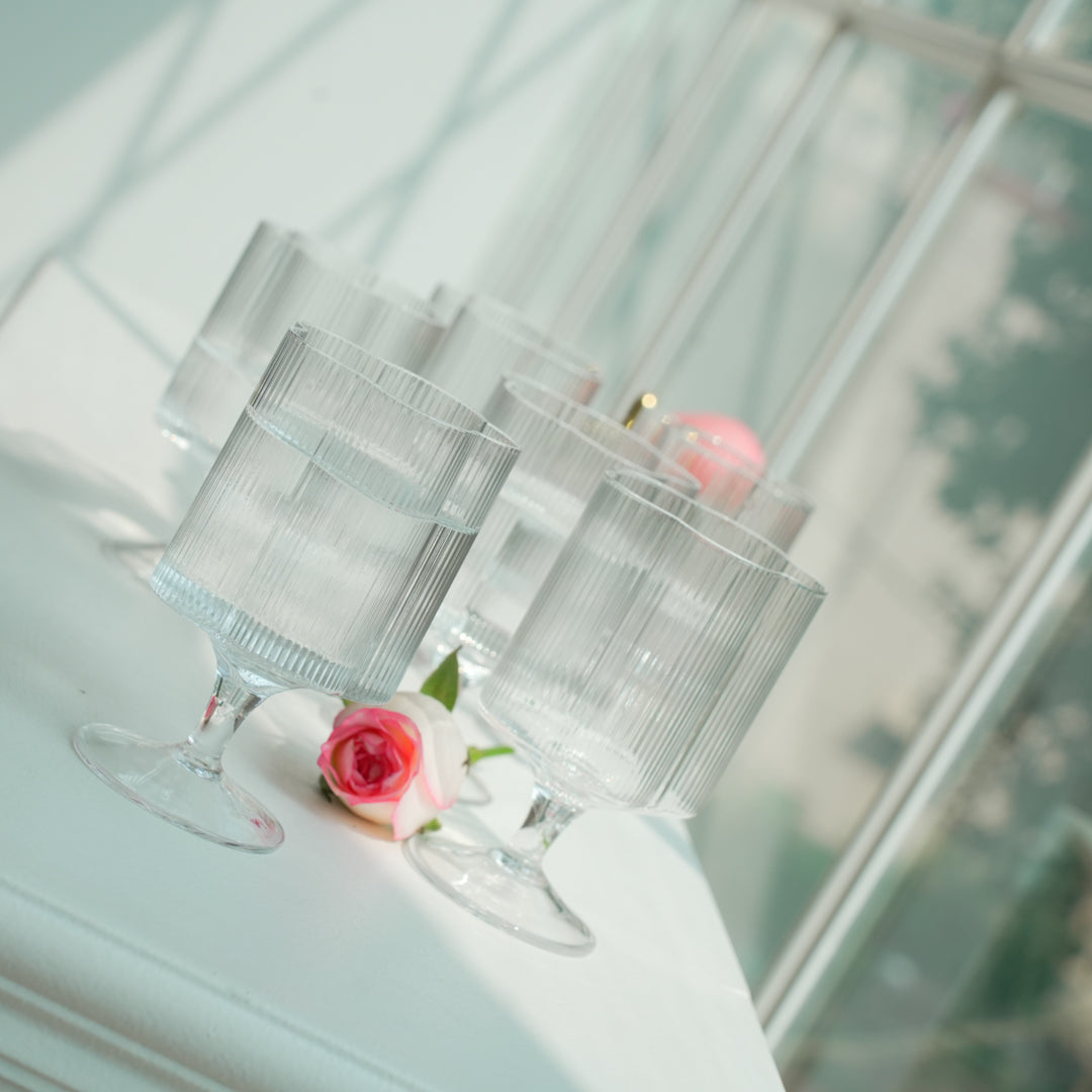 Clear glass goblets with pink flowers on a white surface