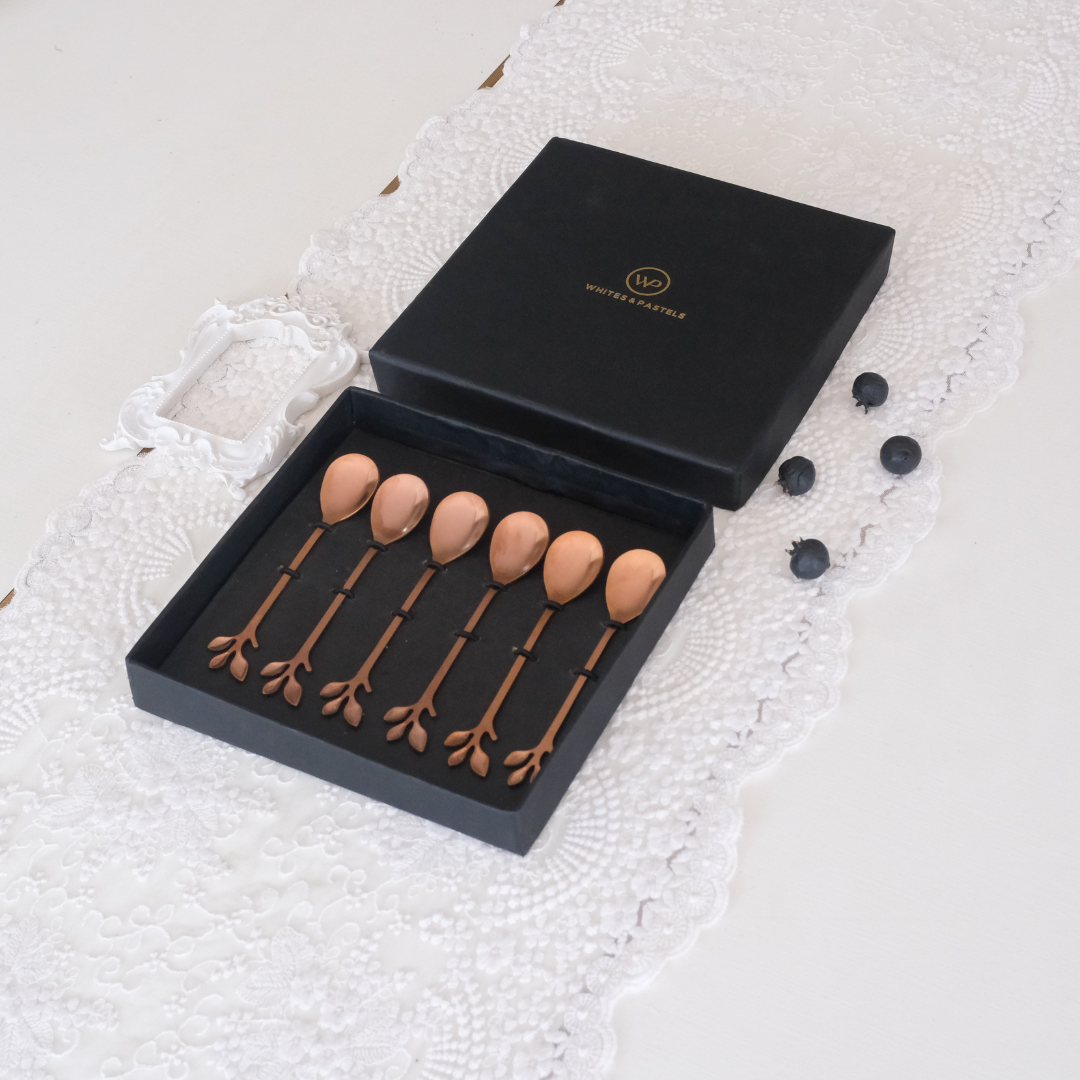 Set of 6 rosegold dessert spoons placed in a giftbox on a white runner