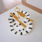 Decorative plate with gold cutlery and black and white striped design on a white surface.