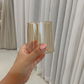 A hand holding a beige amber tinted borosilicate water glass.