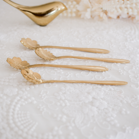 Designer gold spoons showcasing finely carved floral craftsmanship for luxury table décor and entertaining.