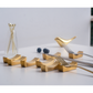 Gold fork and spoon holder on a white surface with a light gray background