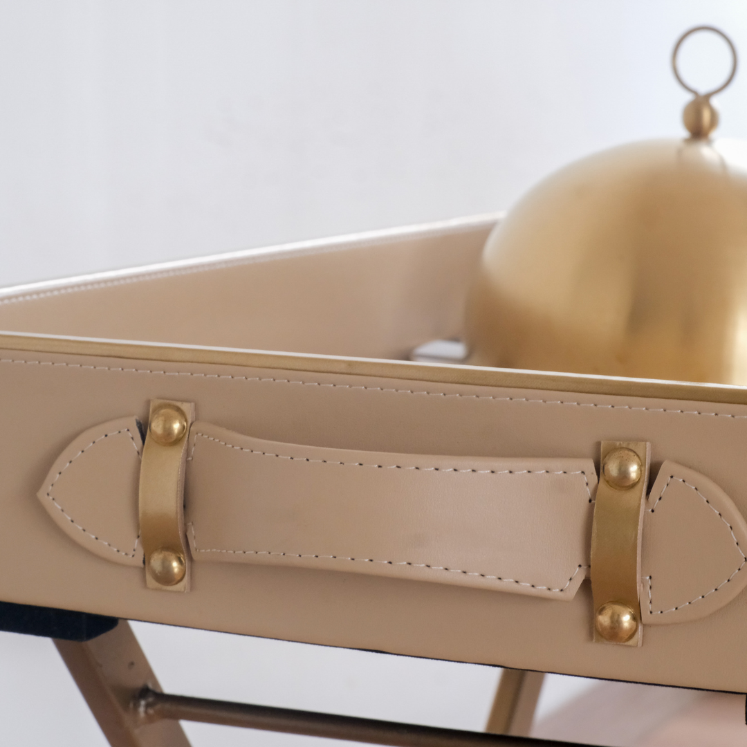 Luxury beige butler tray styled with embossed ceramic tea set and serving cloche for sophisticated entertaining.