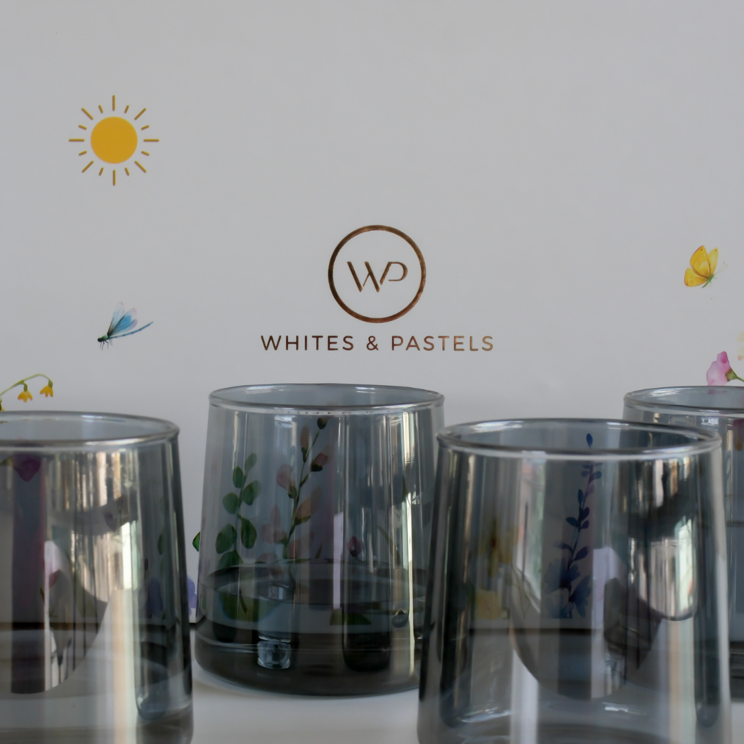 Six black drinking glasses arranged in front of a luxury Whites & Pastels gift box