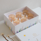 Six brown drinking glasses arranged in front of a luxury Whites & Pastels gift box