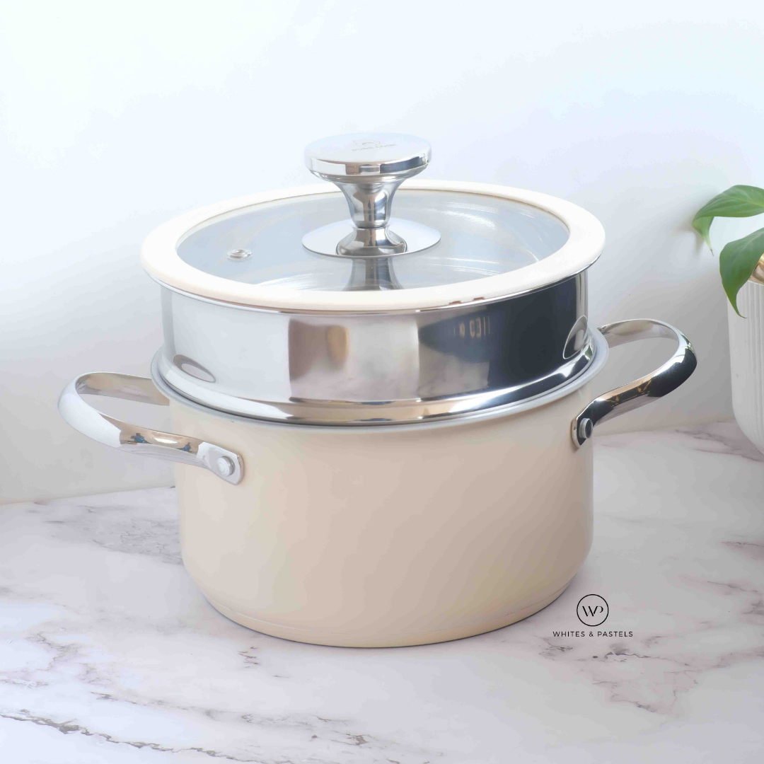 Beige enamel-coated casserole pot with stainless steel rim, glass lid, and side handles, placed on a marble surface