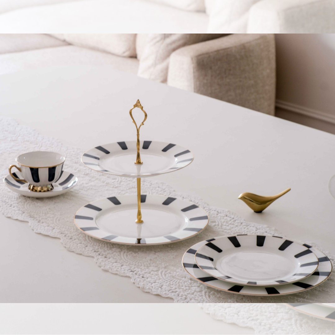 Stylish ceramic high tea serving collection with cake stand, plates, and coffee cup for entertaining guests.
