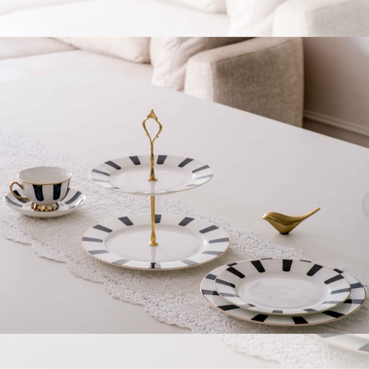 Stylish ceramic high tea serving collection with cake stand, plates, and coffee cup for entertaining guests.