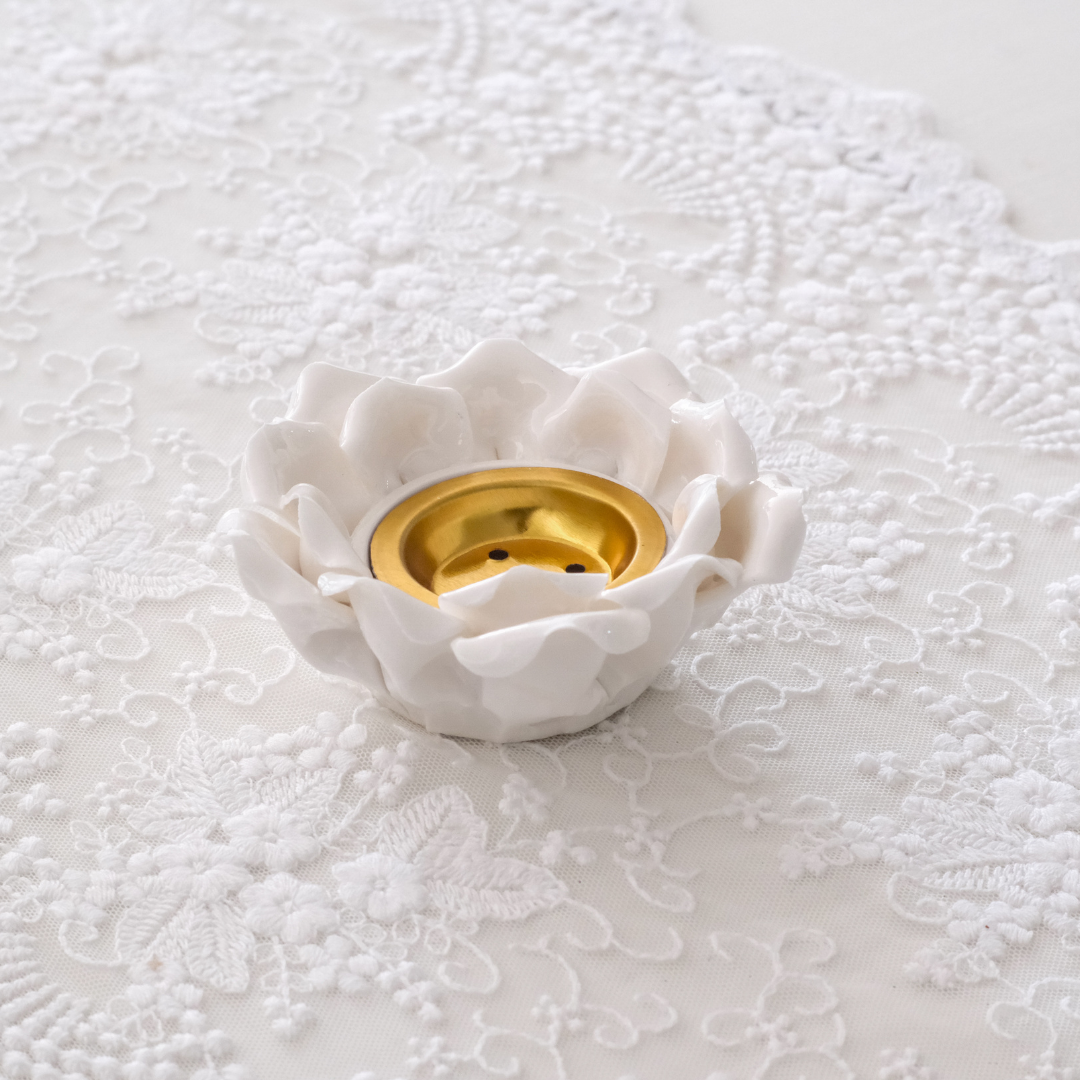 Close-up of glazed ceramic lotus tea light holder with gold center