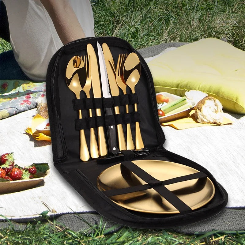 A cutlery set for two people displayed in a carry bag, with the set including knives, forks, and spoons, placed on a picnic setting.