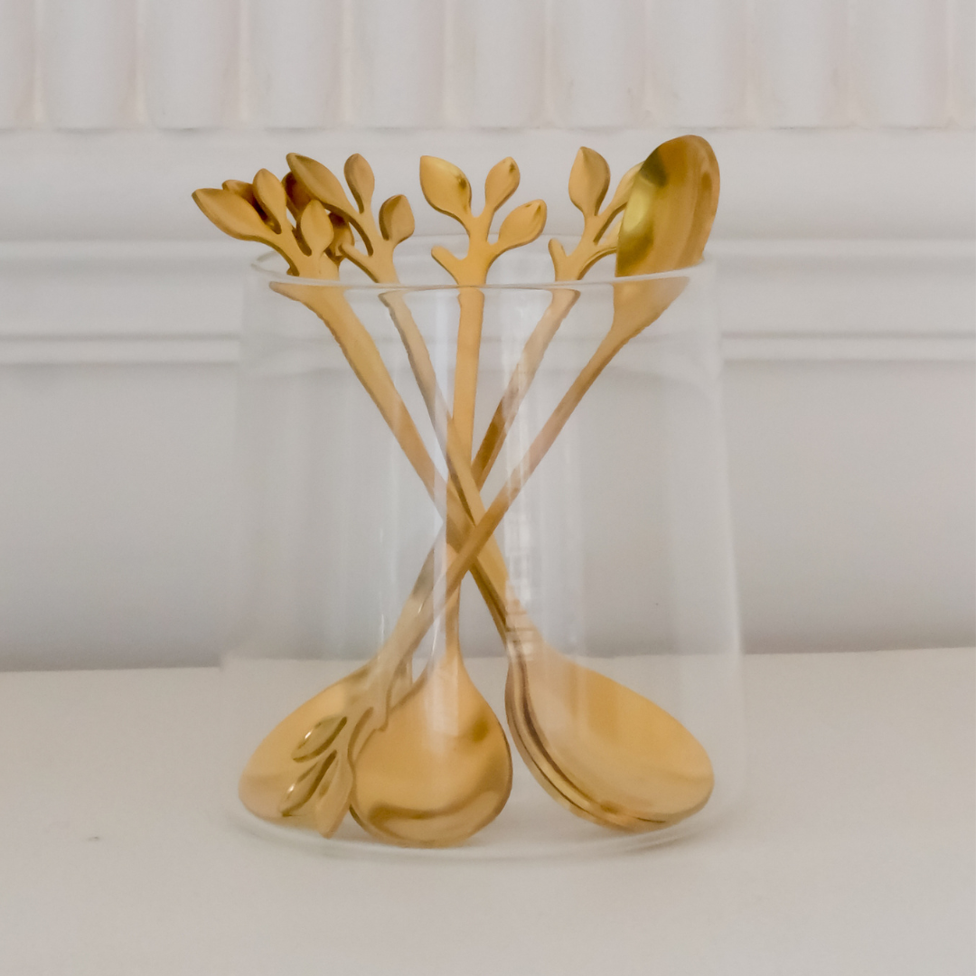 Modern gold leaf dessert spoons displayed on a white ceramic plate for stylish serving