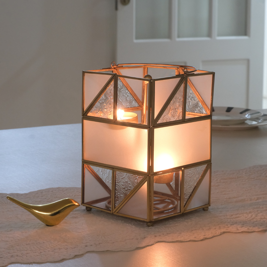 Decorative gold candle holder lantern with frosted glass panels for modern interiors.