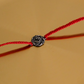 Close-up of a handcrafted Pure Silver Om Rakhi featuring an elegant silver Om symbol on a traditional red thread.