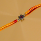 Designer floral pure silver rakhi with intricate flower motif and pink gemstone on a handcrafted yellow-red thread for Raksha Bandhan.