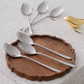 Premium gold spoon fork collection displayed on a rustic wooden platter.