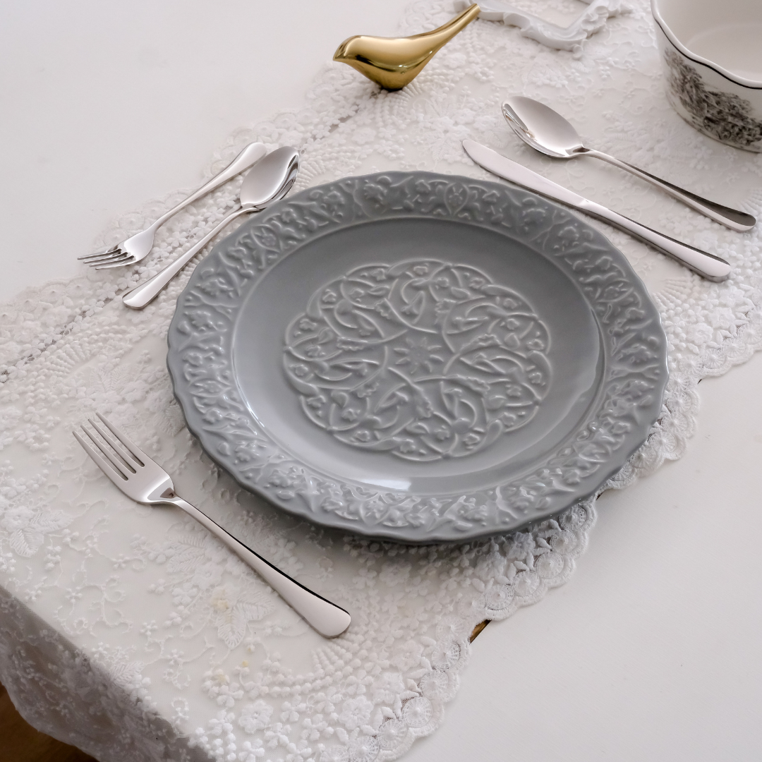 set of luxury silverware set on white runner and a grey engraved plate