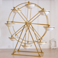A gold metal Ferris wheel decorative stand with eight white ceramic bowls, set against a white paneled wall and light wood floor.