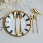 Gold PVD dinnerware set including a spoon, fork, and knife, arranged on a white plate with black stripes and a gold rim, alongside a gold bird-shaped object on a light gray surface.