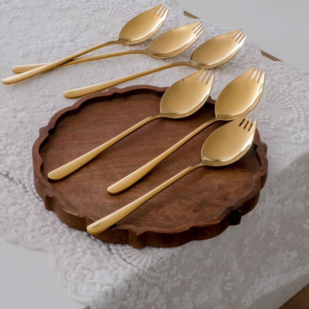 Luxury gold stainless steel spoon and fork hybrid cutlery set displayed on a wooden serving tray.