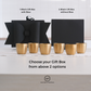 Six small metallic gold cups are arranged on a white surface in front of two black gift boxes, one with a large bow and one plain. Text reads '1.