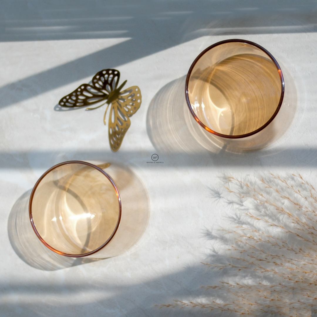 Top view of 2 brown glasses with natural sunlight and a beautiful butterfly as decor piece