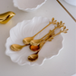Modern gold leaf dessert spoons displayed on a white ceramic plate for stylish serving