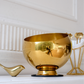 Elegant contemporary gold snack bowl displayed in a minimalist luxury interior setting.