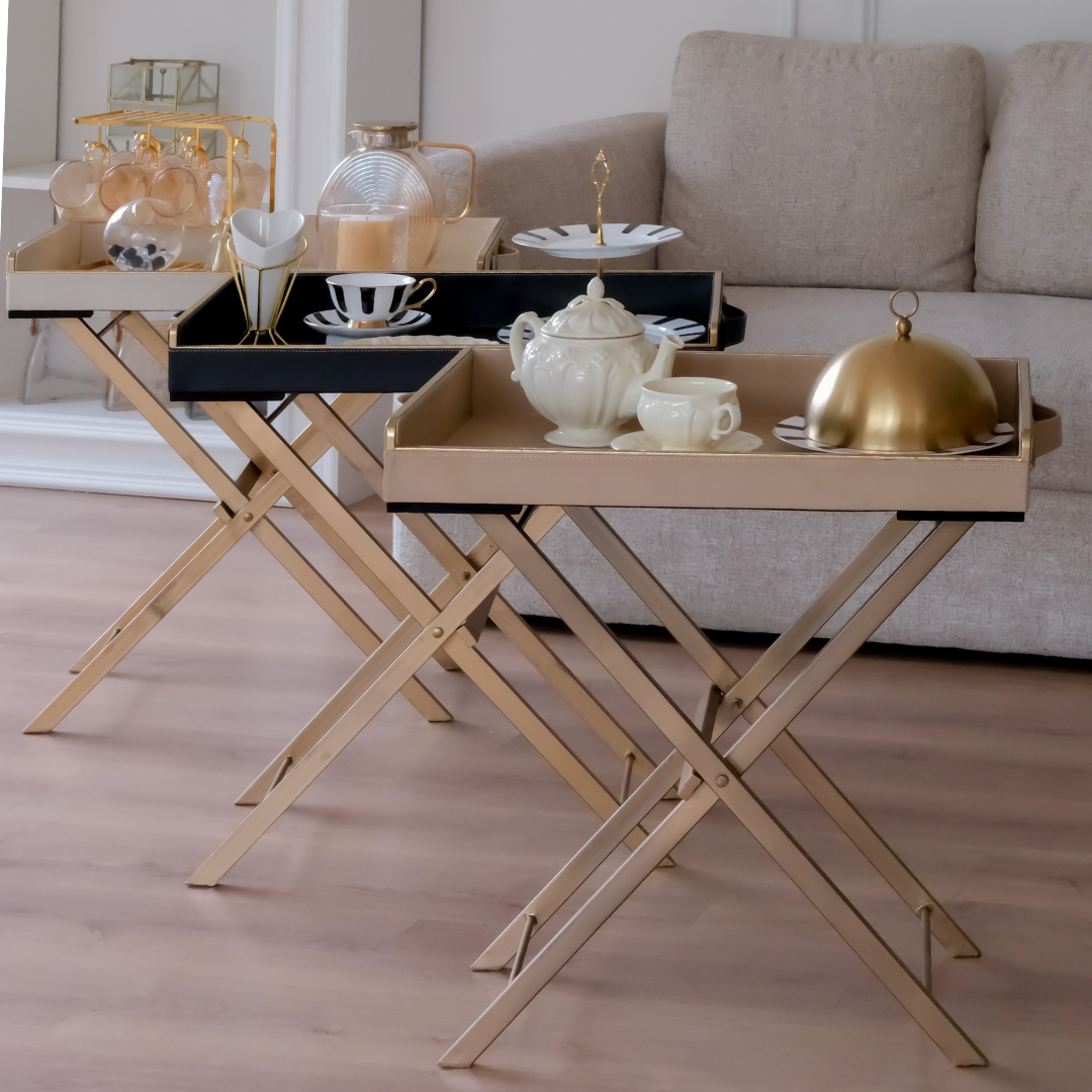 Three luxury folding butler trays in beige and black finishes styled for elegant tea serving and home entertaining.