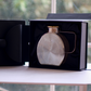 Brown glass jug with gold lid presented alongside premium black luxury gift packaging