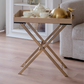 Elegant beige folding butler tray placed beside a sofa with a tea set, perfect for serving guests.