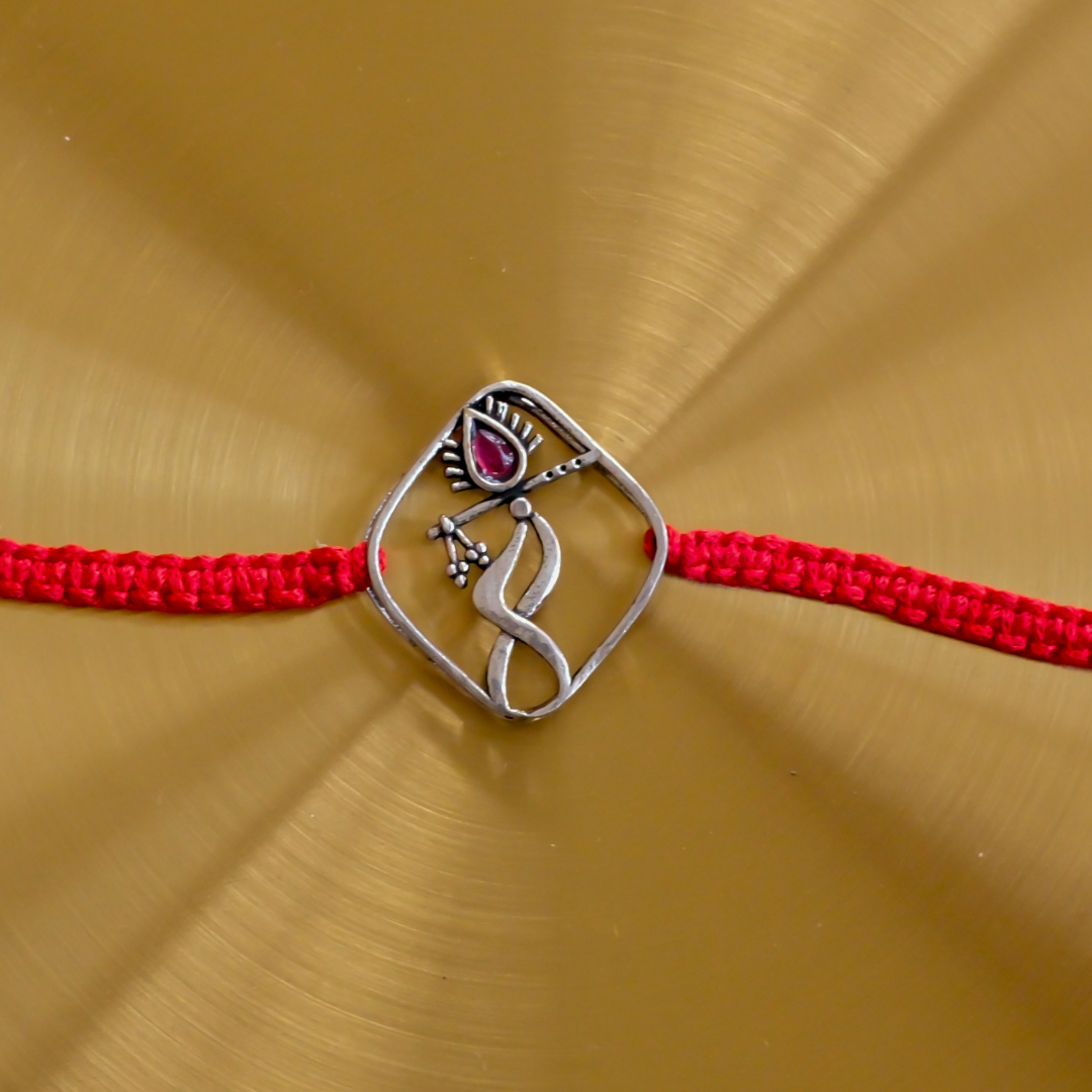  Pure Silver Dancing Krishna Rakhi with a ruby-red accent and premium red thread, designed as a meaningful Raksha Bandhan gift.