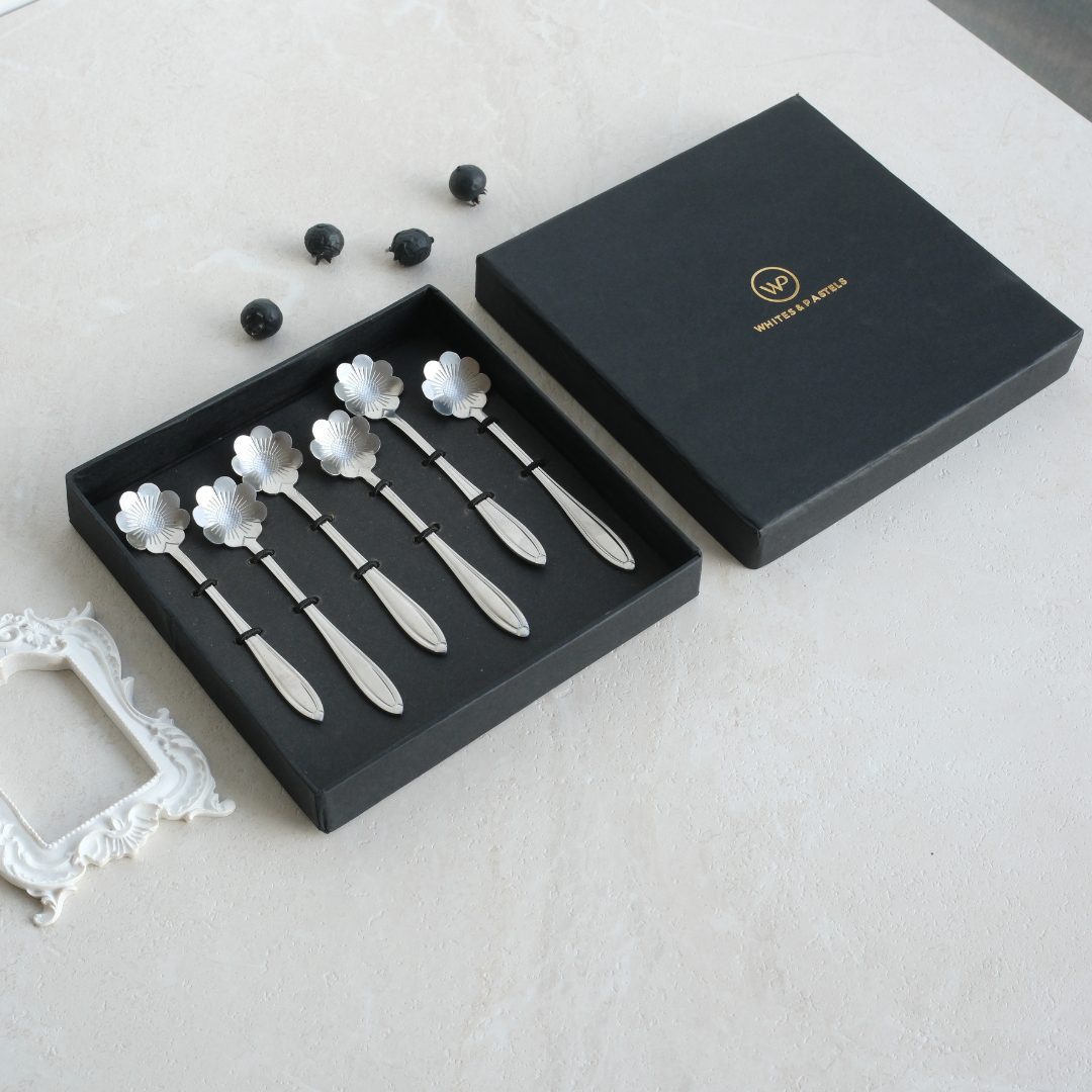 6 beautiful floral shaped dessert spoons placed inside a black giftbox .