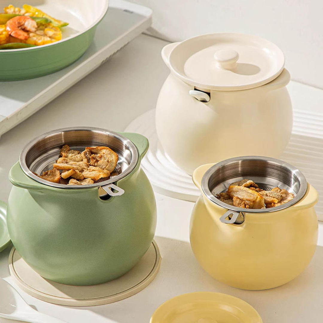 Three ceramic Ghee Pot containers in sage green, cream, and pale yellow, each with a stainless steel inner pot and lid, arranged on a light tabletop with food visible in the background.