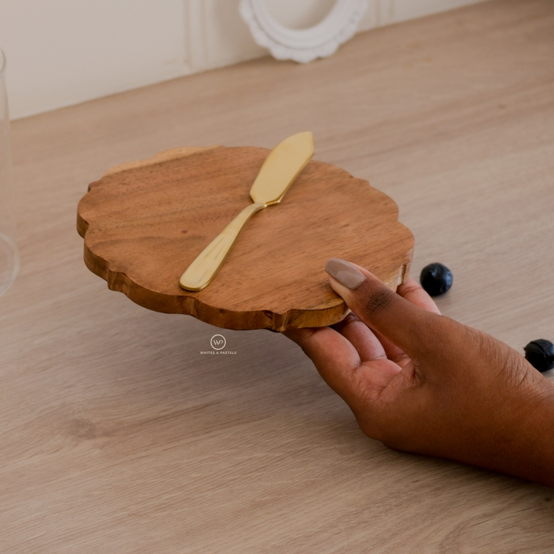 Round wooden board with a gold knife for serving cheese and dips in a womens hand showing the size and thickness