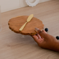 Round wooden board with a gold knife for serving cheese and dips in a womens hand showing the size and thickness