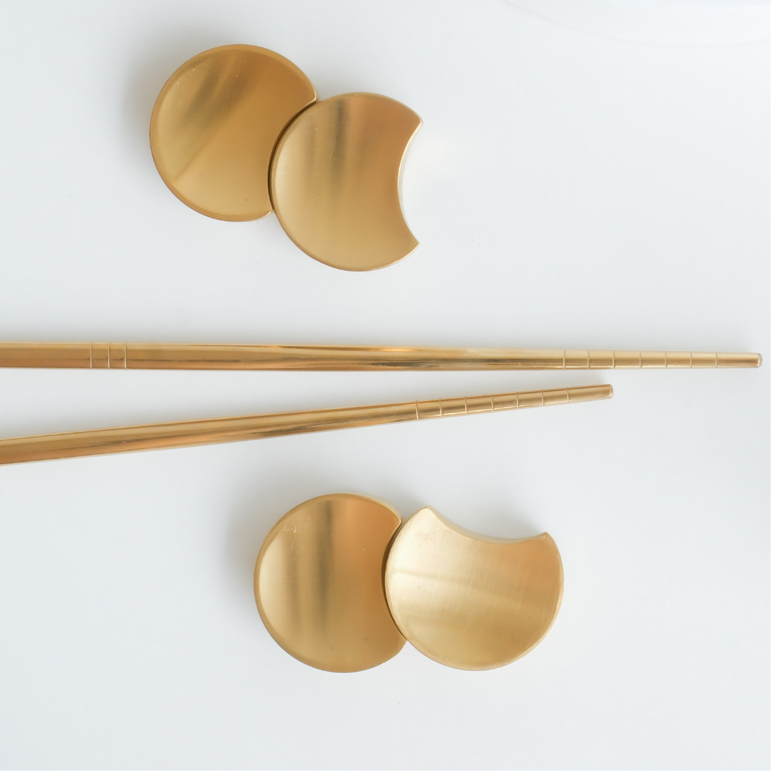 Gold chopsticks with gold ends on a white background