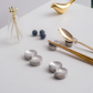 Silver chopstick holders and gold spoon on a white surface