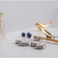 Decorative items including a gold bird, silver candle holders, and blueberries on a light gray background showcasing silver spoon rest