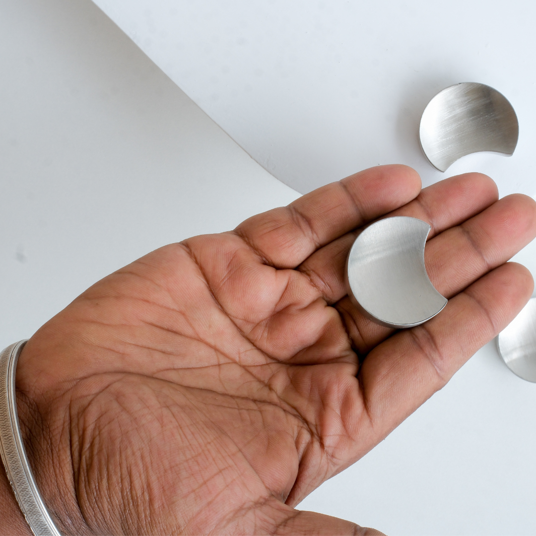 Hand holding a metal poon rest against a white background