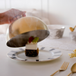 Dessert being served on a decorative plate with a gold and black cover