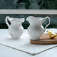Victorian ceramic milk creamer jugs in pink floral and ivory finishes with elegant embossed detailing, perfect for tea serving, coffee stations and luxury dining.