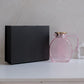 Pink glass jug with gold lid and handle, photographed with a luxury black gift box