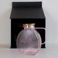 Pink glass serving jug with gold lid and sleek handle for stylish beverage serving