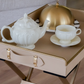 Front view of a beige folding butler tray featuring a removable serving tray and sturdy metal stand.