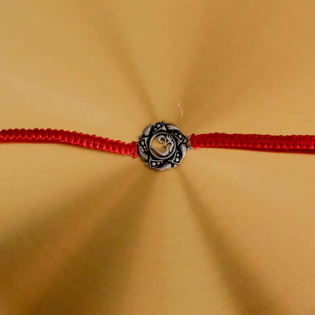 Premium handcrafted Pure Silver Om Rakhi with genuine silver centerpiece and adjustable red braided thread for Raksha Bandhan.