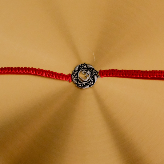 Premium handcrafted Pure Silver Om Rakhi with genuine silver centerpiece and adjustable red braided thread for Raksha Bandhan.