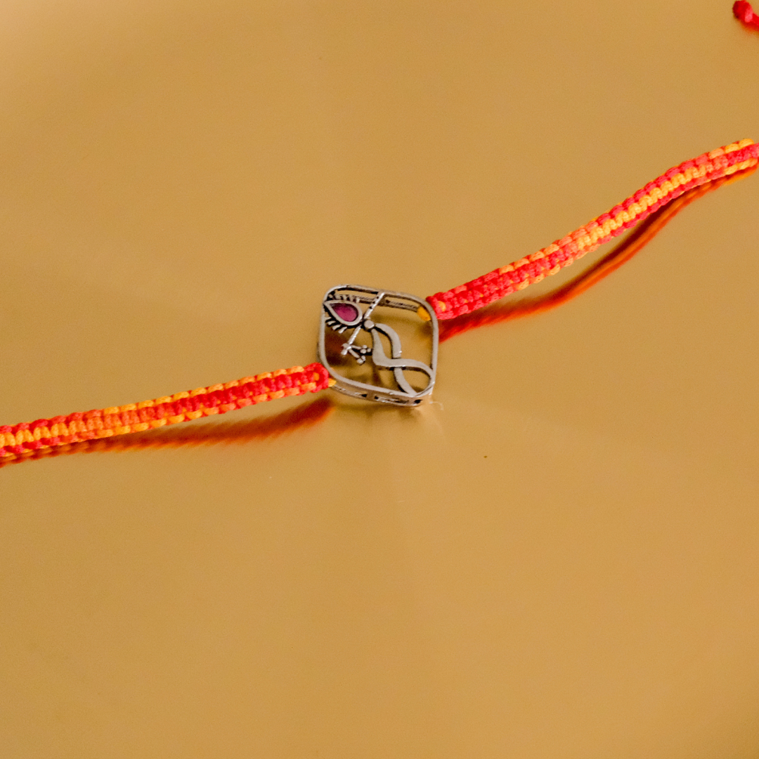 Pure Silver Dancing Krishna Rakhi featuring a handcrafted Lord Krishna motif with a ruby-red stone and vibrant red braided thread for Raksha Bandhan.