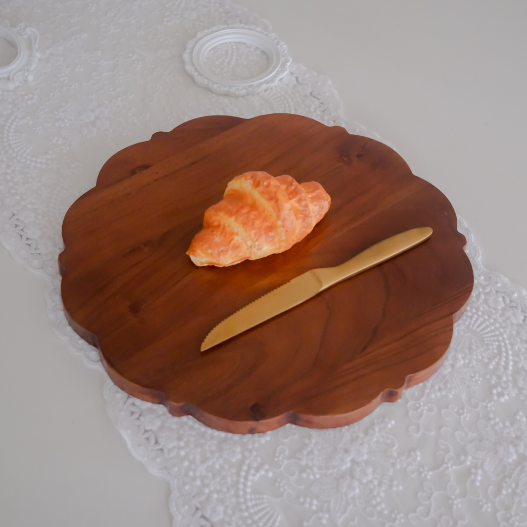 A Croissant on cutting board with Dinner Knife