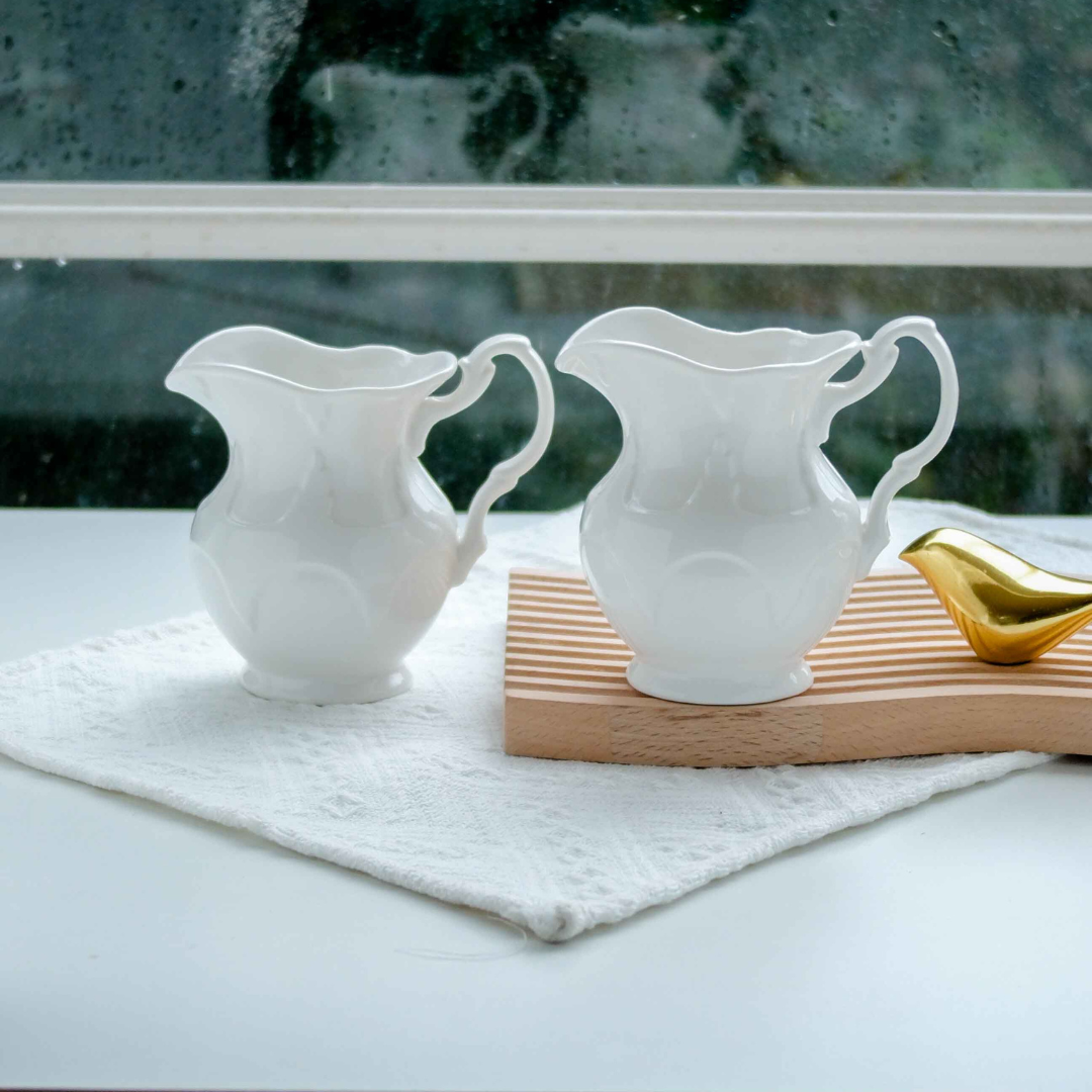 Minimalist  ceramic creamer pitchers with decorative handles, ideal for serving milk, cream and dessert sauces on modern dining tables.